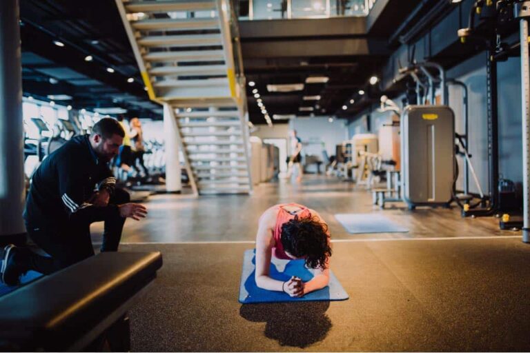 Coaching a lady to do the plank.