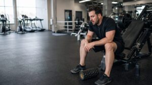 Tired man sitting beside a leg press after doing. too much during his warm-up